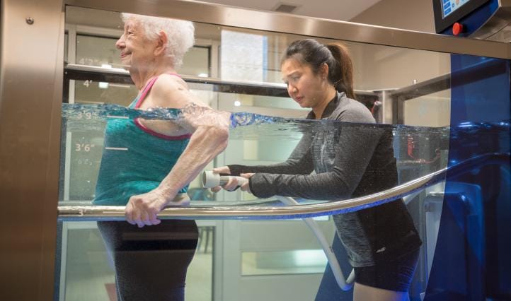 Senior resident in therapy with staff assistance in water