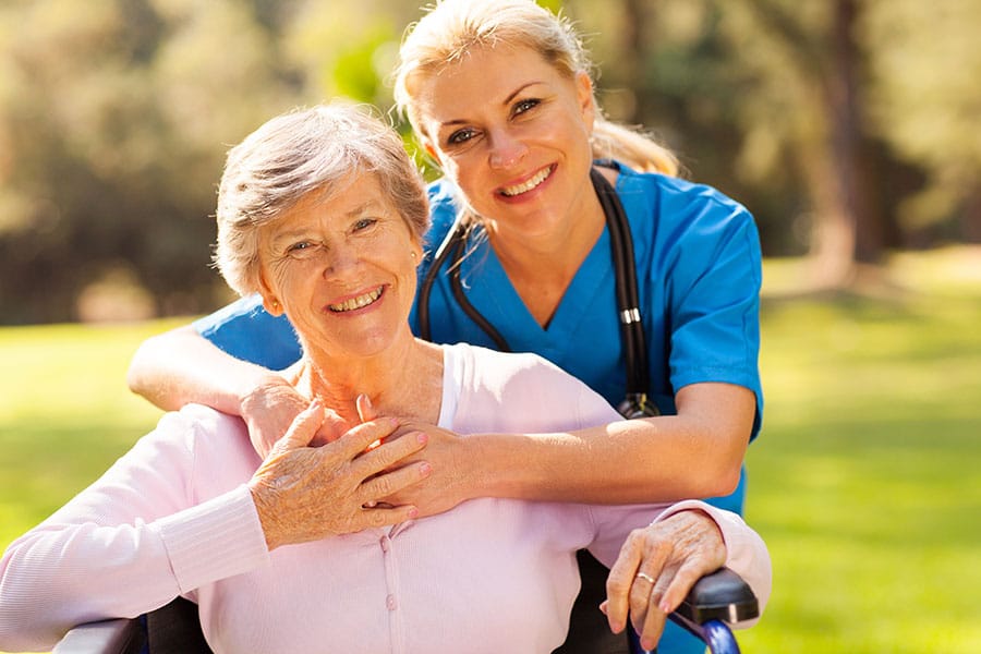 A caregiver and resident smiling in a garden