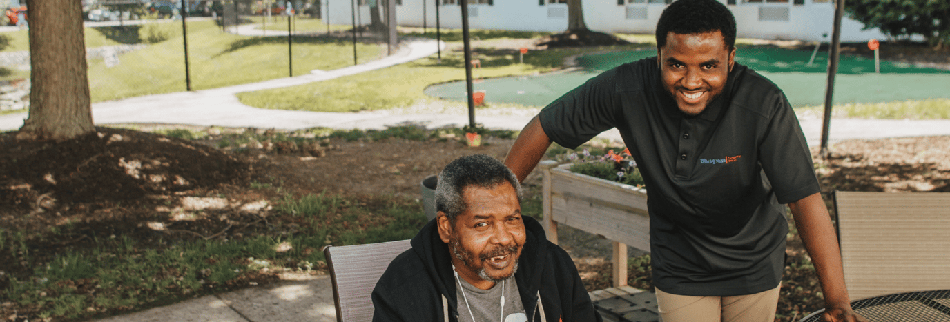 A resident and staff member smiling in an outdoor space
