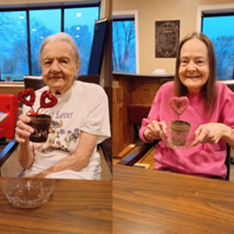 Two residents smiling with heart-shaped desserts