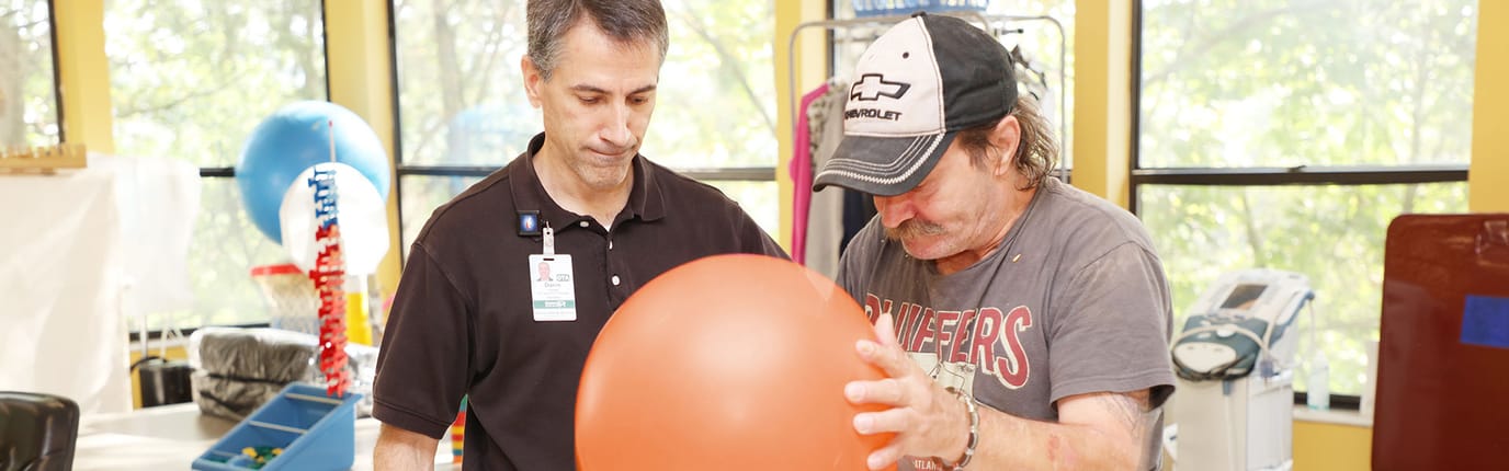Therapist assisting a resident with a therapy ball