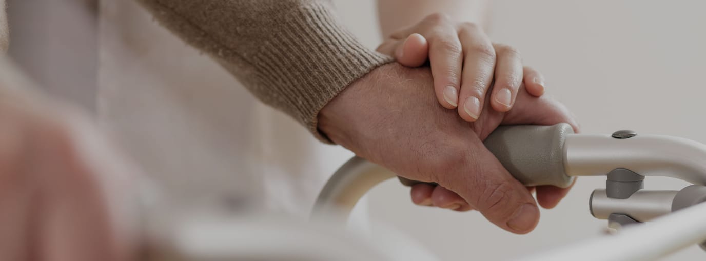 Close-up of hands on a walker, symbolizing care