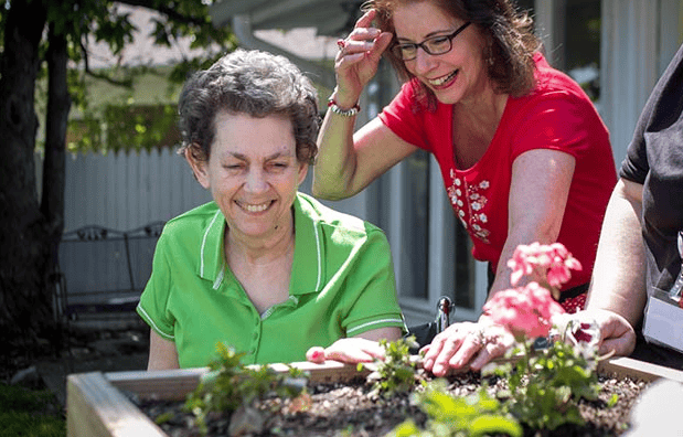 Residents gardening outdoors with staff assistance