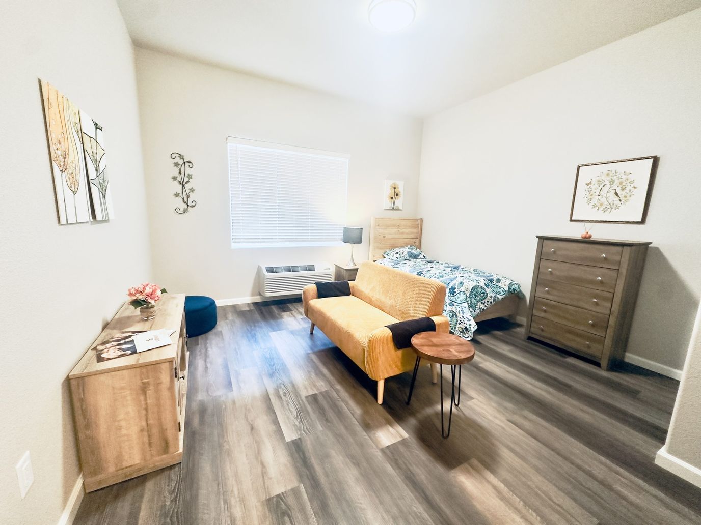 A well-furnished resident room with a bed and seating area
