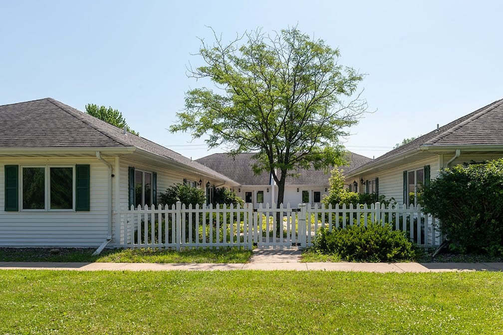 Exterior view of the facility with a white fence and trees
