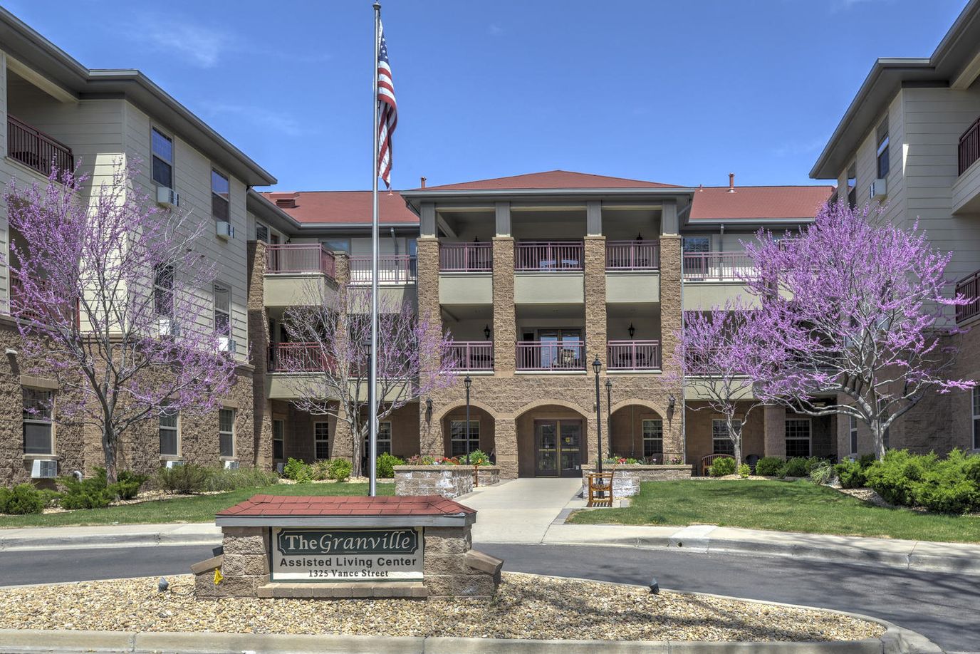 Exterior view of Granville Assisted Living Center with flowering trees