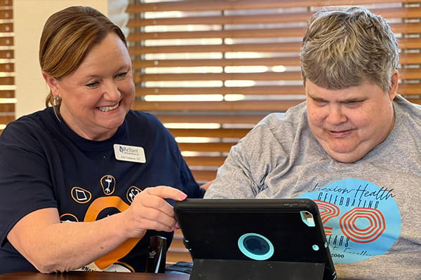 Staff member assisting a resident with a tablet