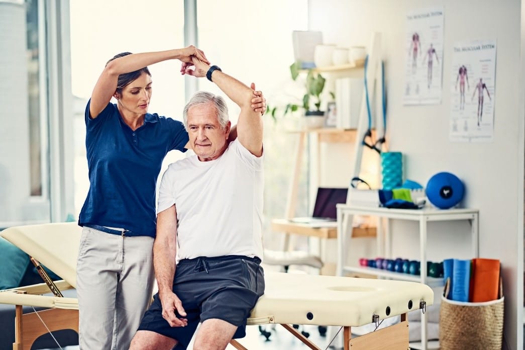 Therapist assisting a senior man in a rehabilitation session