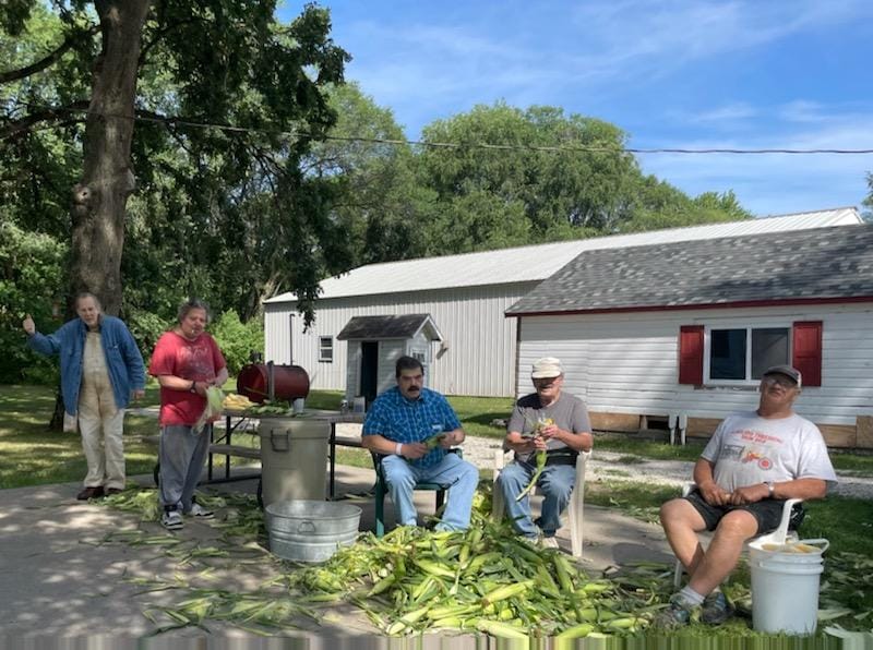 Residents enjoying an outdoor corn-shucking activity