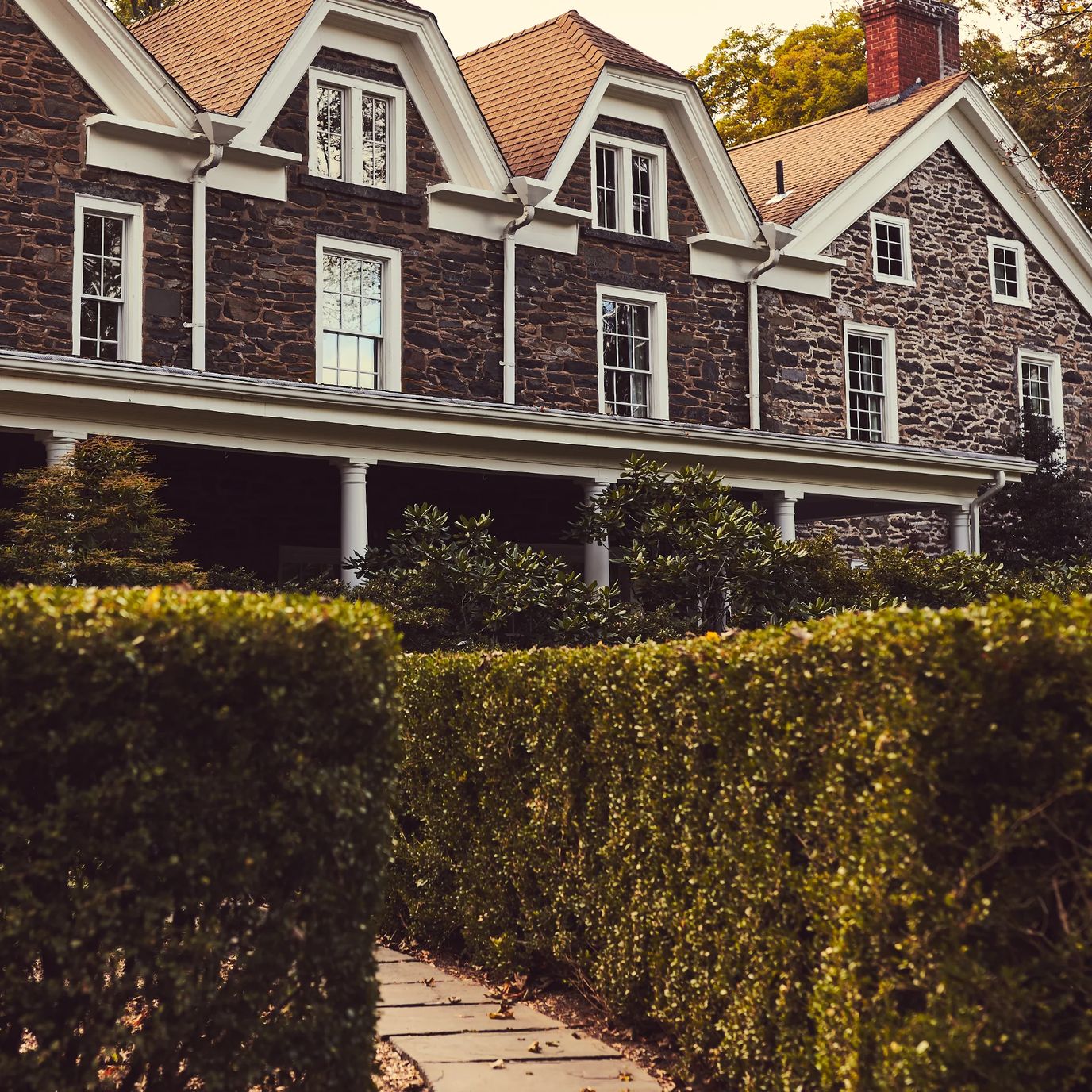 Exterior view of a stone building with manicured hedges.
