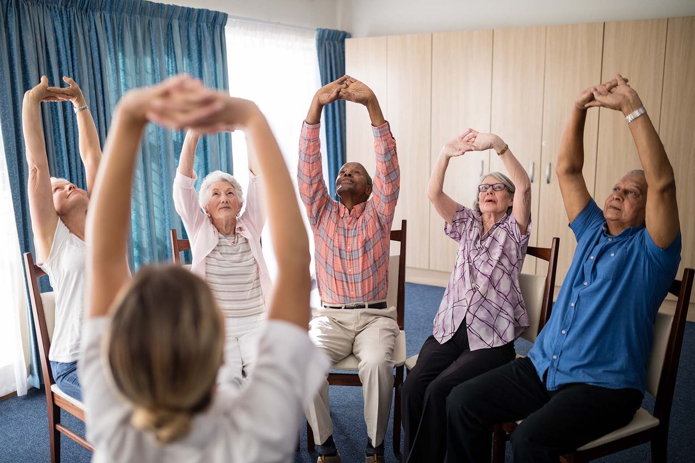 Residents participating in a seated exercise class in the activity room