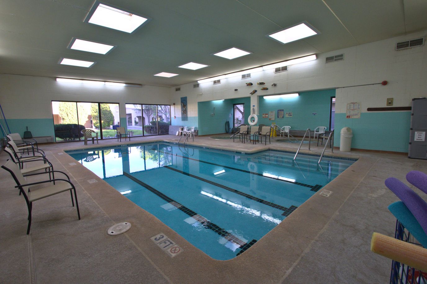 Indoor swimming pool area with chairs and windows