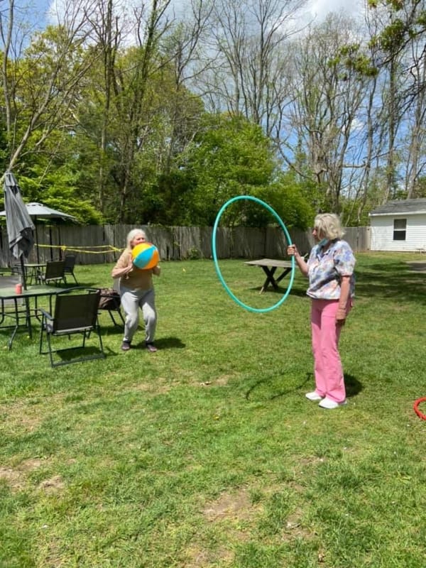 Residents engaging in outdoor activities with a beach ball and hula hoop