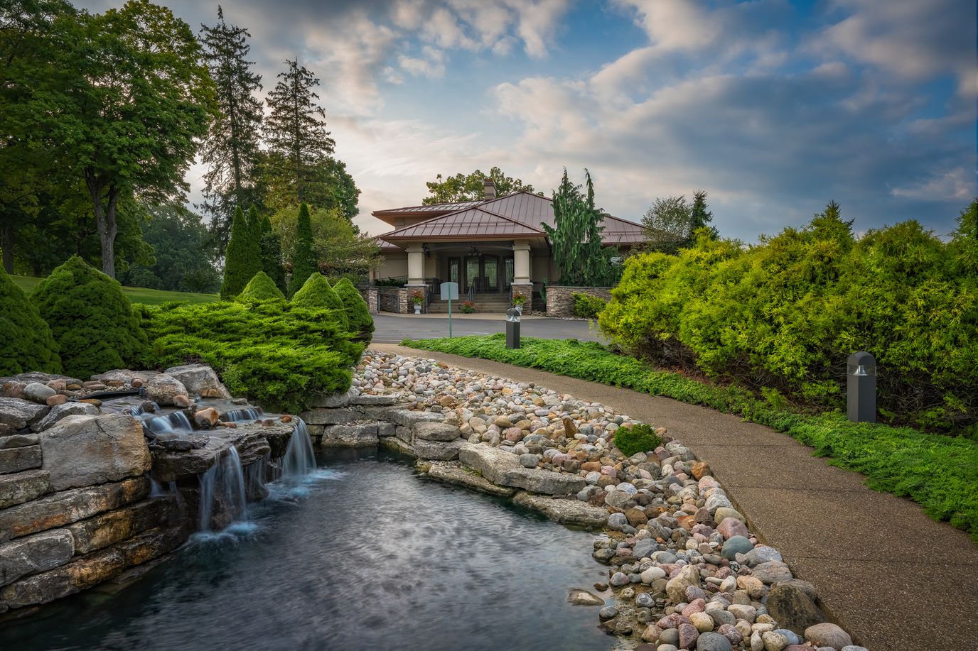 Exterior view of a facility with a landscaped pathway and water feature