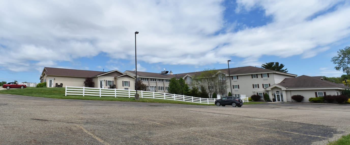 Exterior view of the Senior Suites facility with lawn and parking