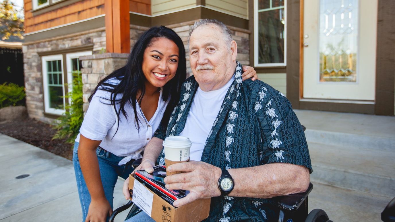 A resident with a staff member outside the facility