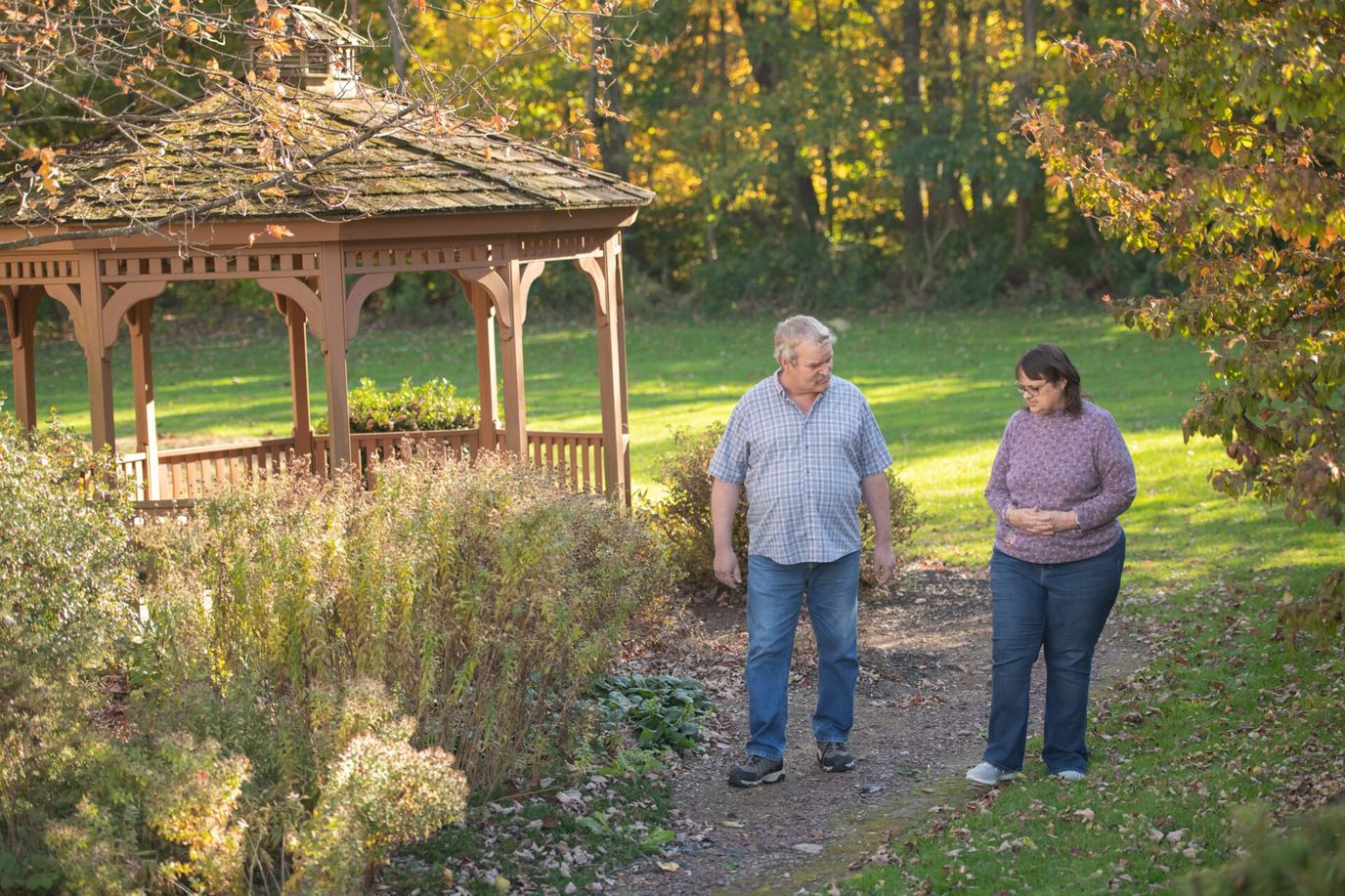 Two residents walking in a garden near a gazebo