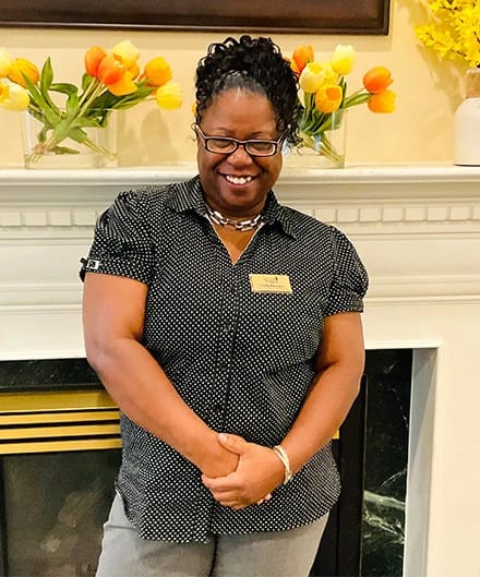 Staff member smiling in a common area with flowers
