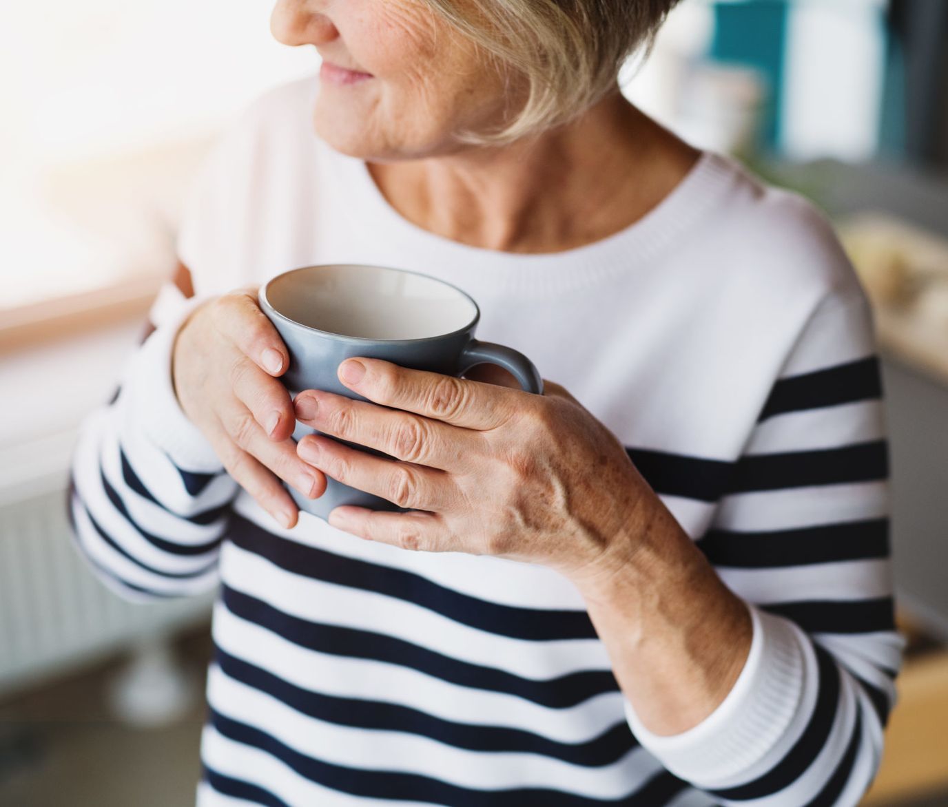 Senior woman enjoying a warm drink with a cozy atmosphere