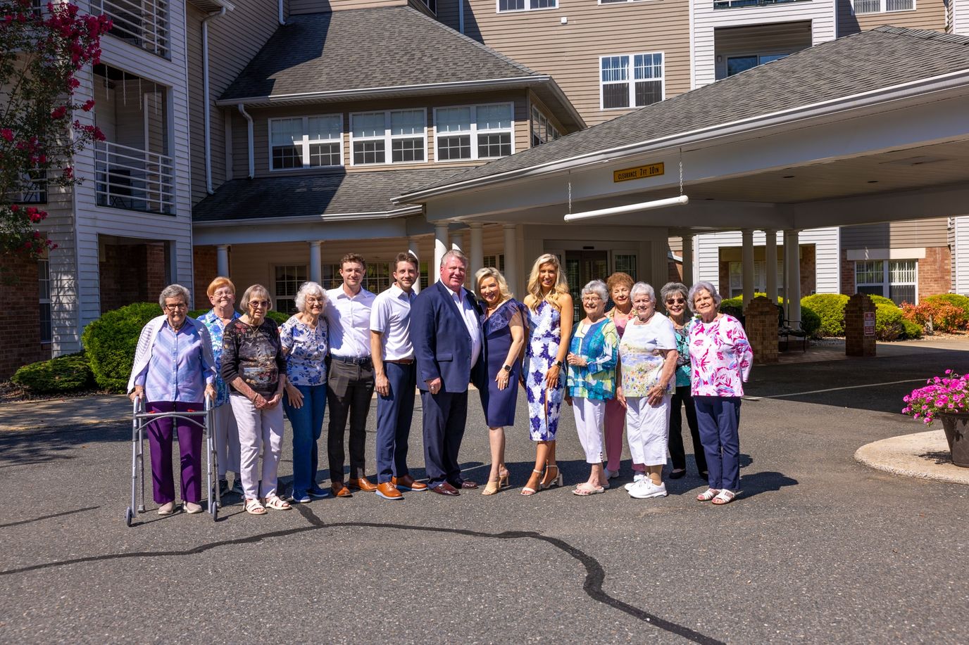 Group photo of residents and staff outside the facility entrance