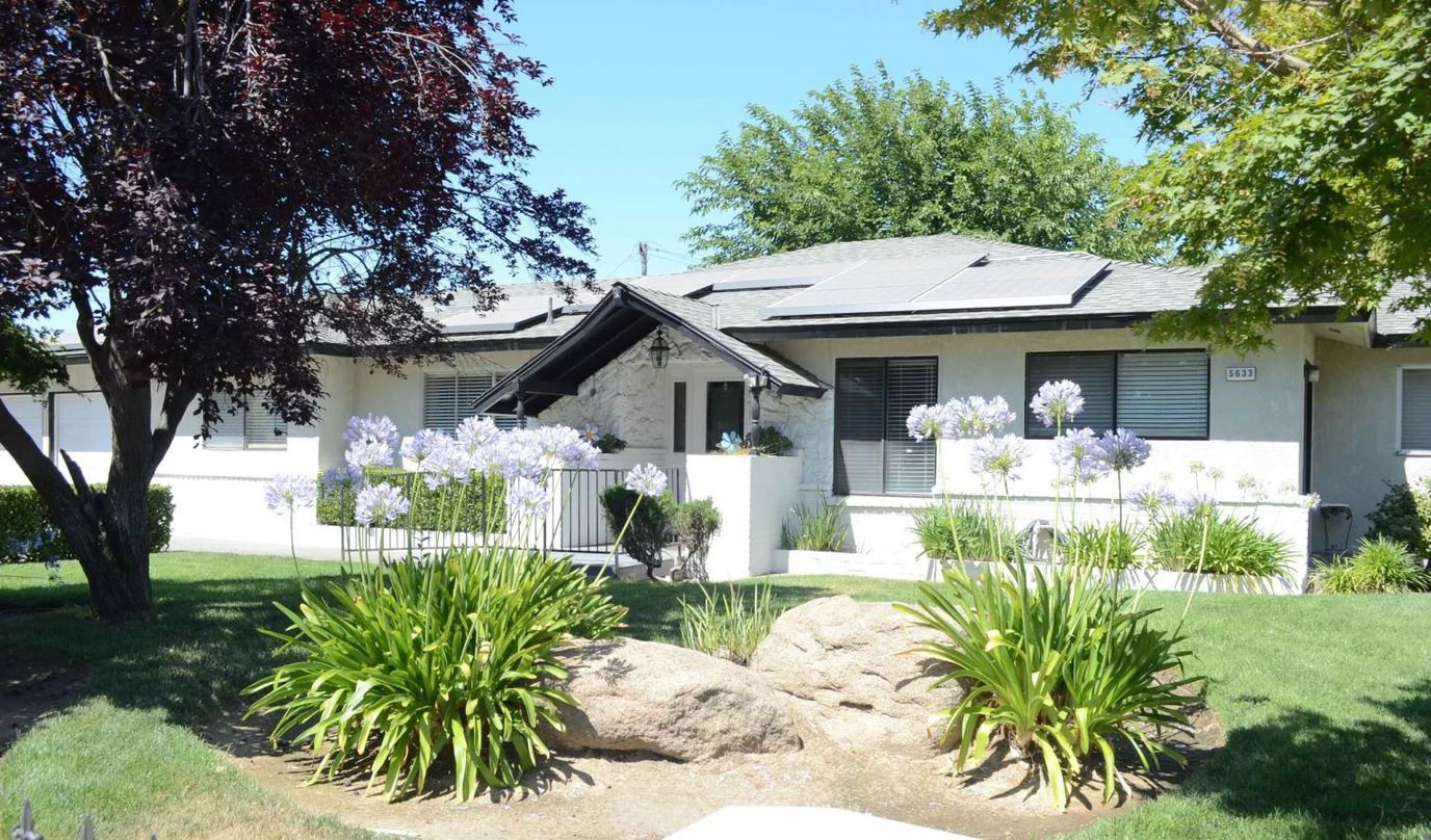 Exterior view of a senior living home with flowers and greenery
