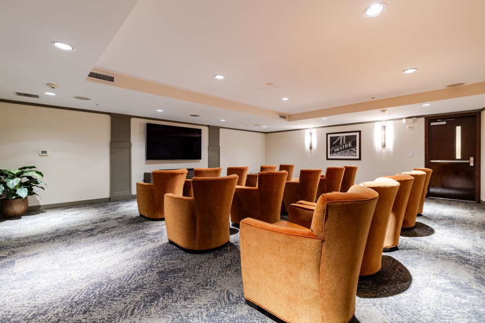 Cozy common area with orange chairs and a TV.