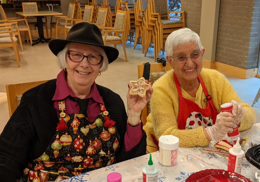 Two elderly women decorating cookies