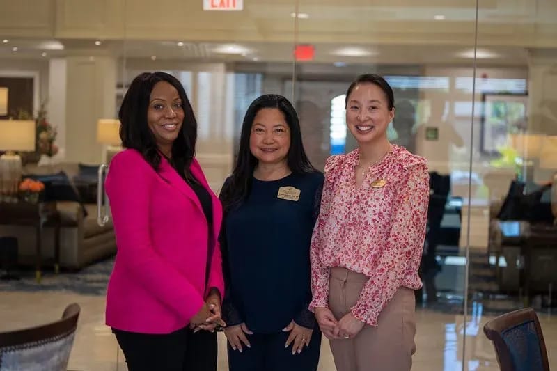 Three staff members in a welcoming lobby area.