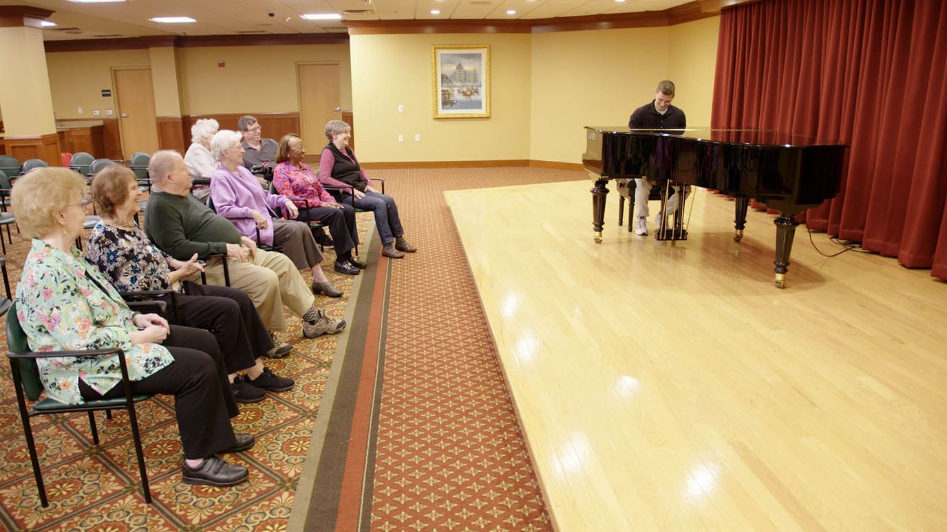 Residents enjoying a piano performance in a common area