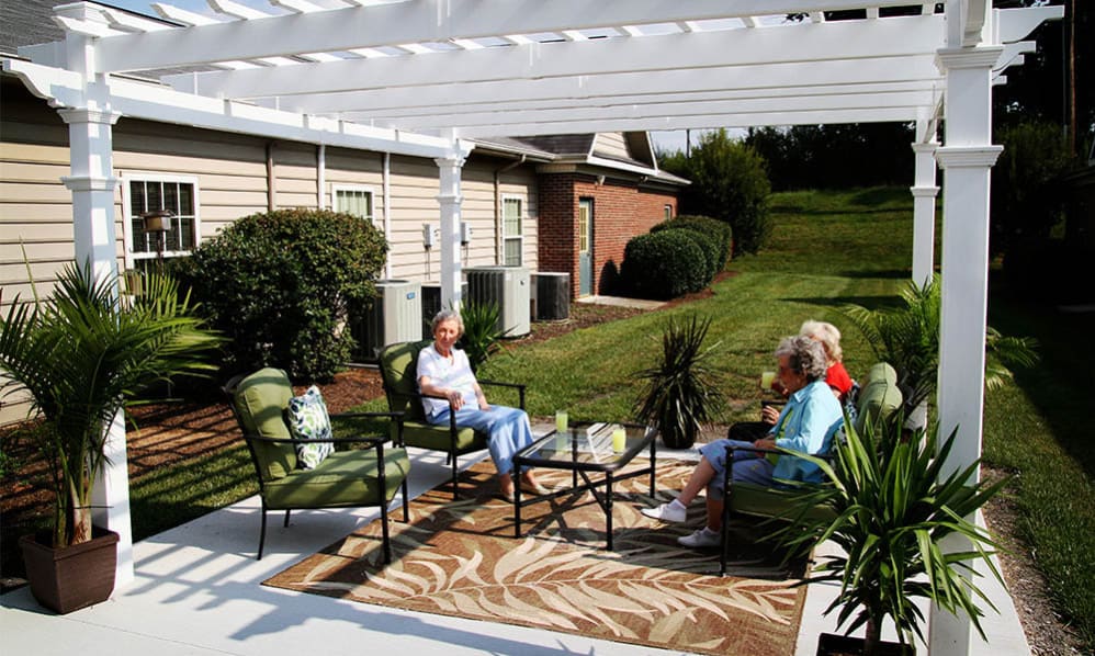 Residents enjoying refreshments on the patio under a pergola