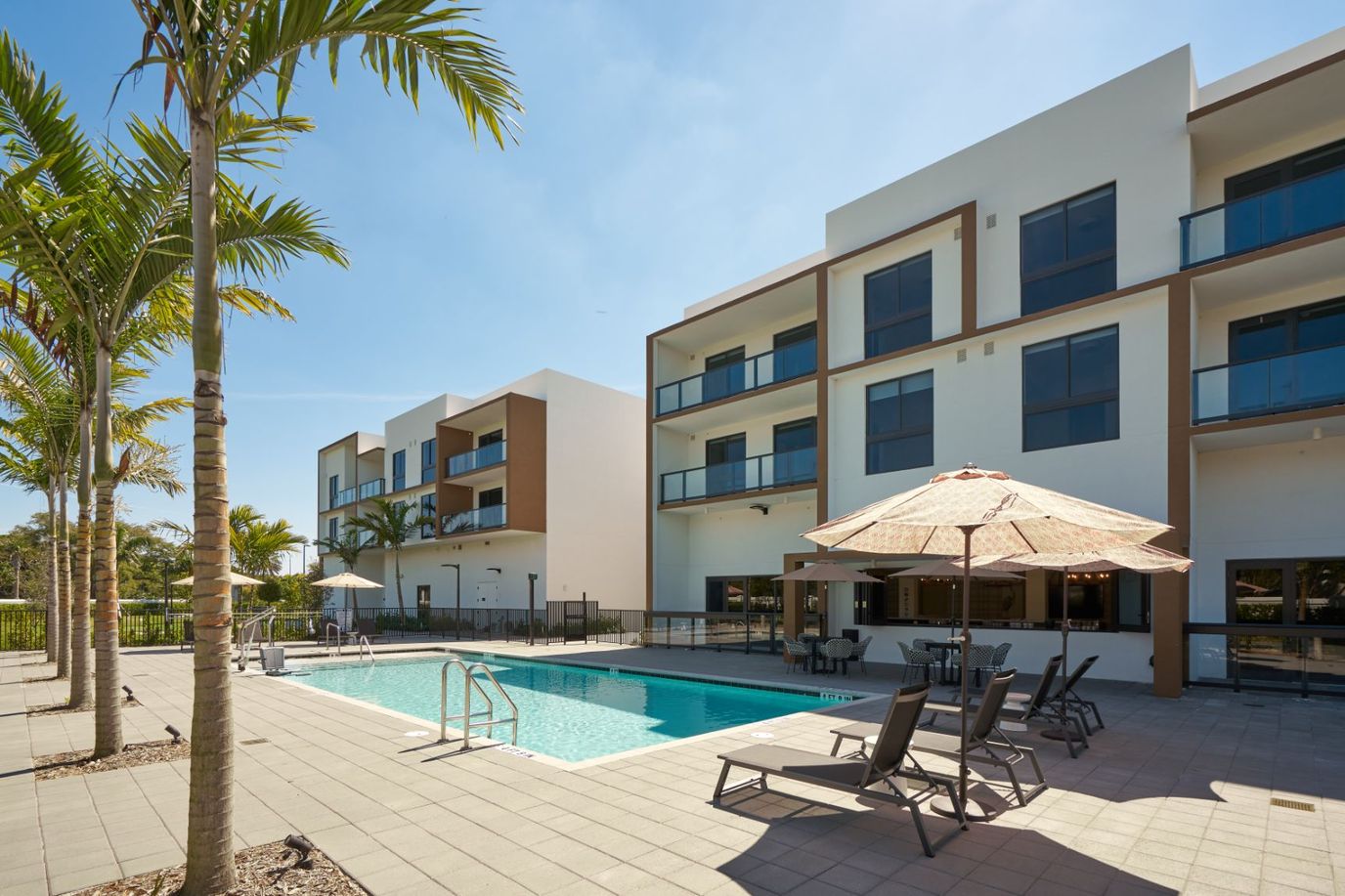 Outdoor pool area with lounge chairs and umbrellas.