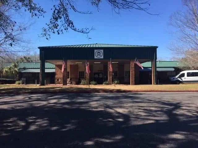 Exterior view of Crowne Health Care facility with flags