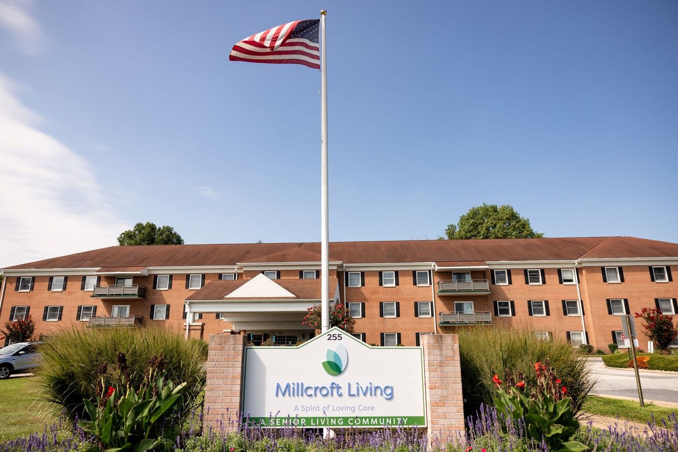 Exterior view of Millcroft Living with flag and sign