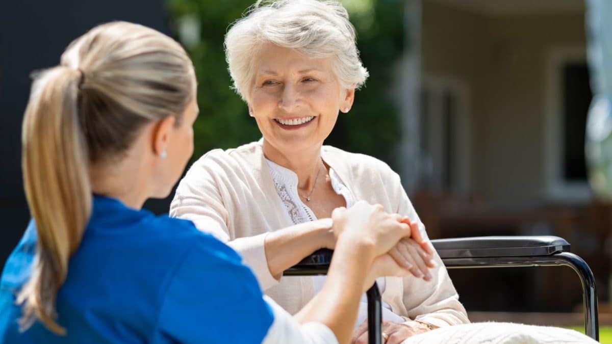A caregiver and a resident chatting outdoors.