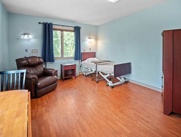 Private resident room with bed and armchair