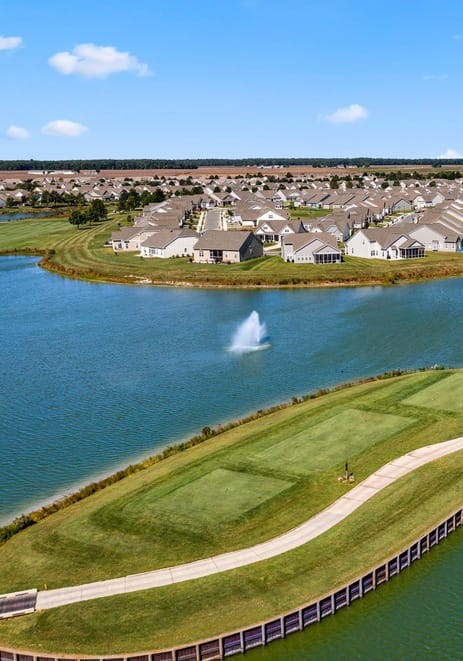Heritage Shores – New Home Discovery Center, independent living in Bridgeville, DE — Aerial view of a tranquil lake with landscaped surroundings