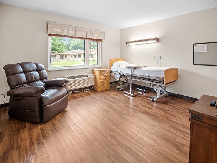 A private resident room with a medical bed and recliner
