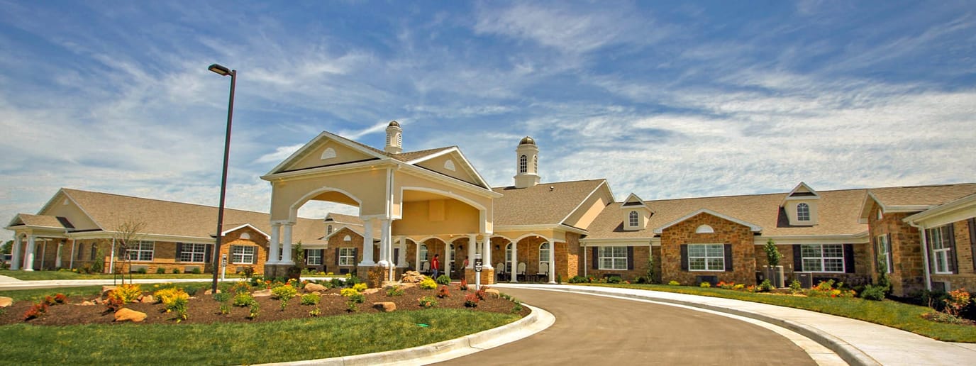 Exterior view of a senior living facility with garden and driveway