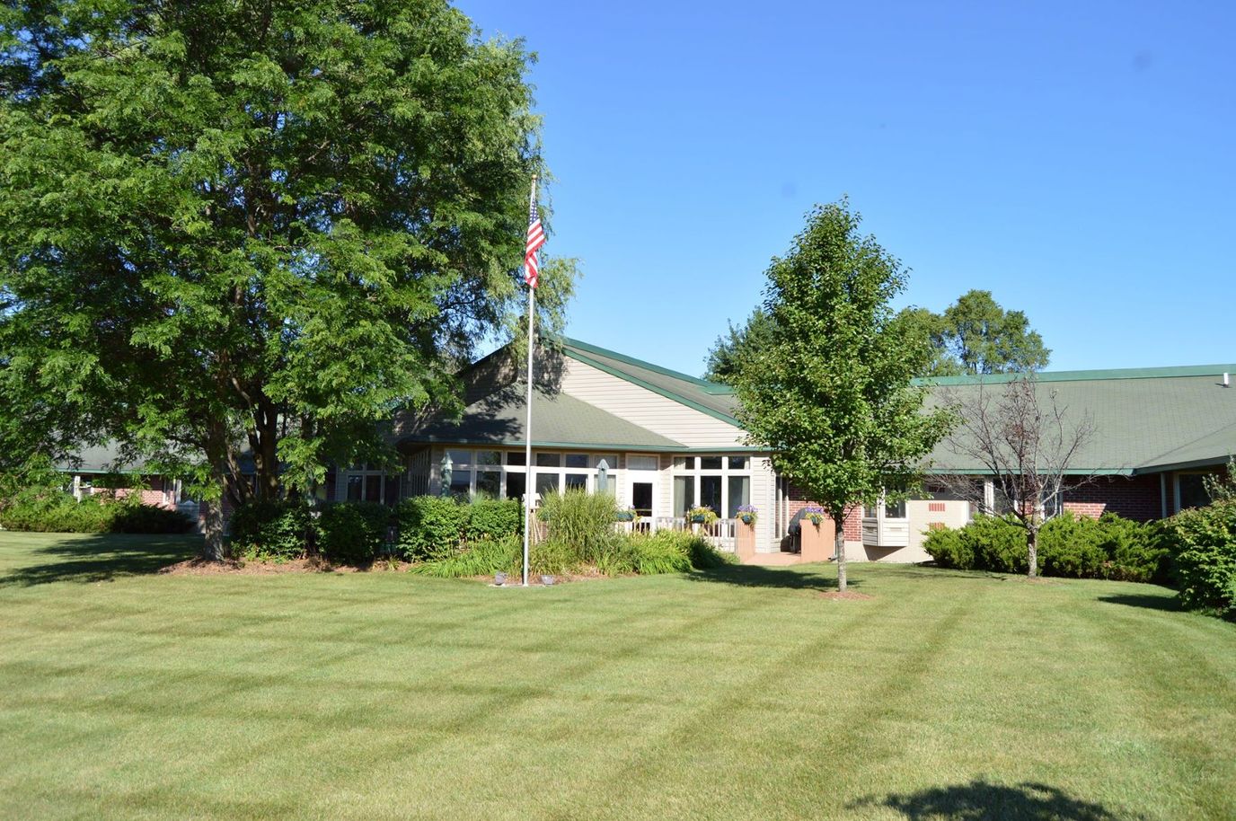 Exterior view of a senior living facility with trees and lawn