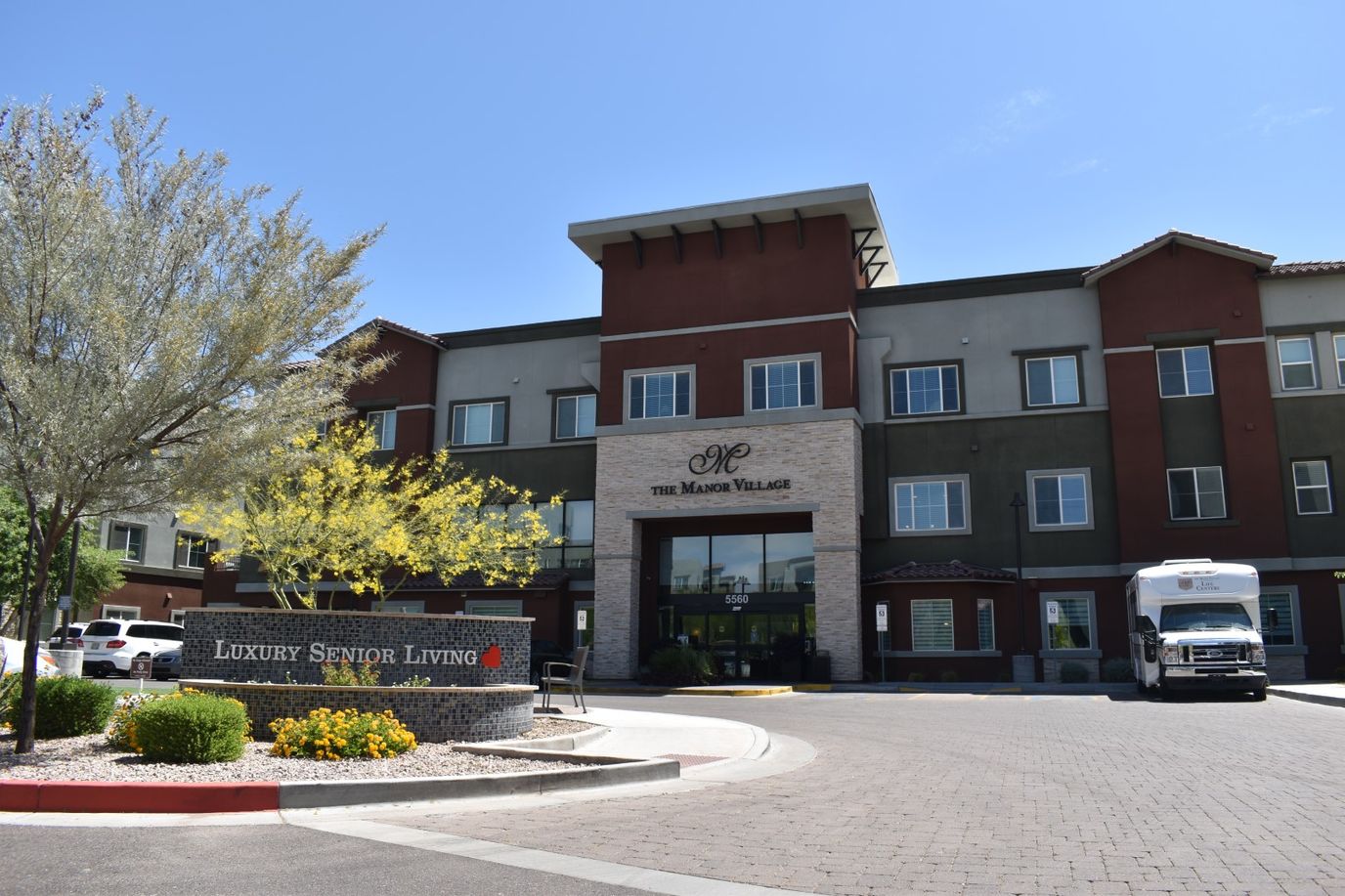 Exterior view of Manor Village with landscaping and vehicle