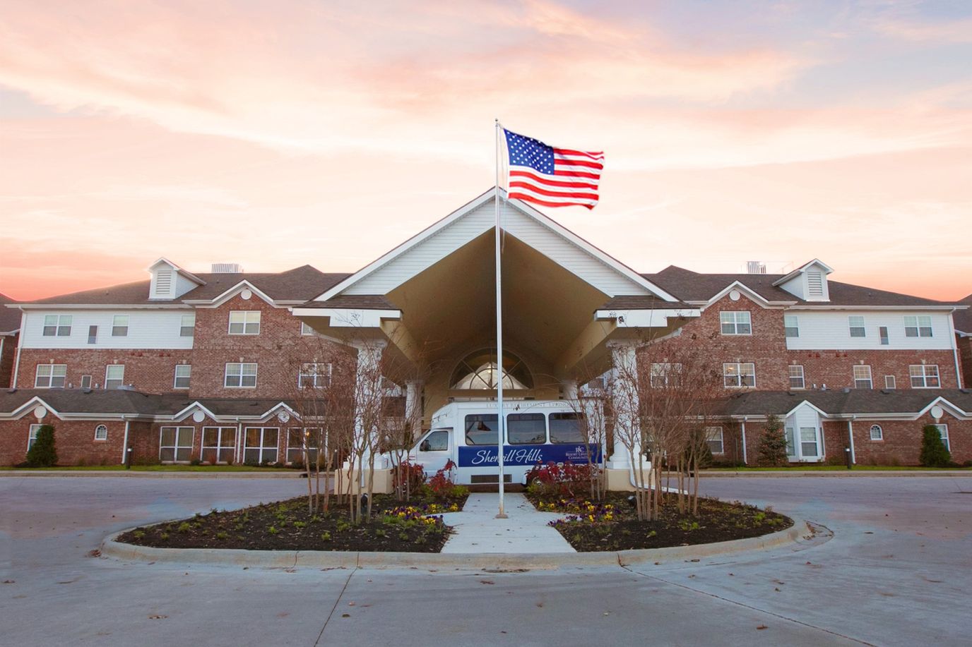 Exterior view of Sherrill Hills Retirement Resort with flag and shuttle
