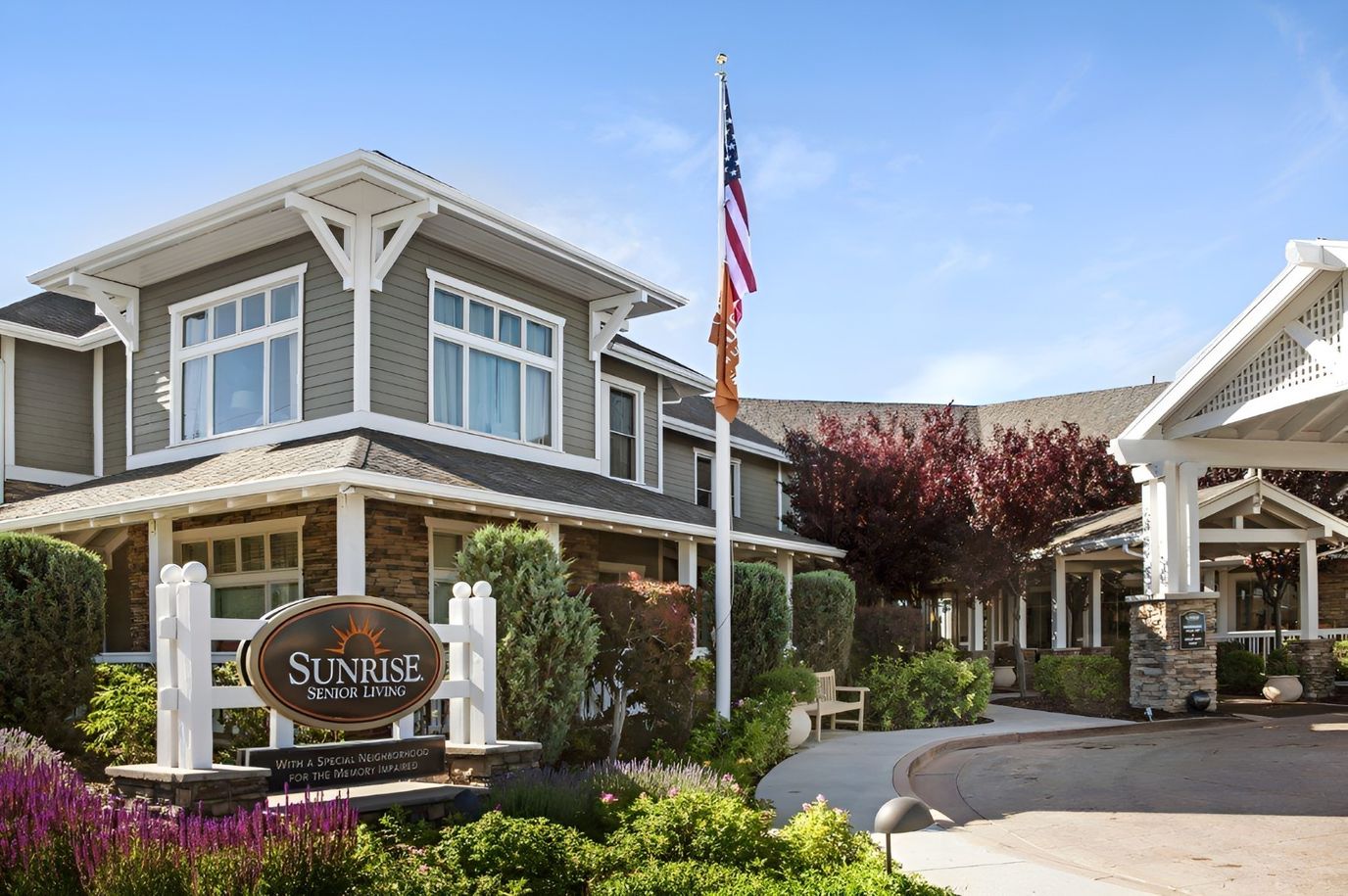 Exterior view of Sunrise Senior Living facility with flag and sign