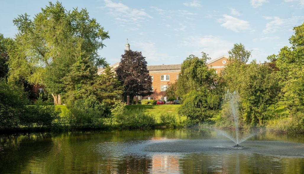View of a serene pond with fountain and facility in background