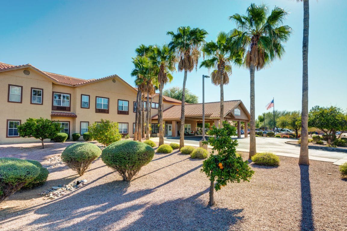Front exterior view of a senior living facility with palm trees