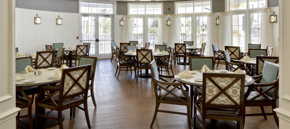 Dining room with neatly set tables and chairs.