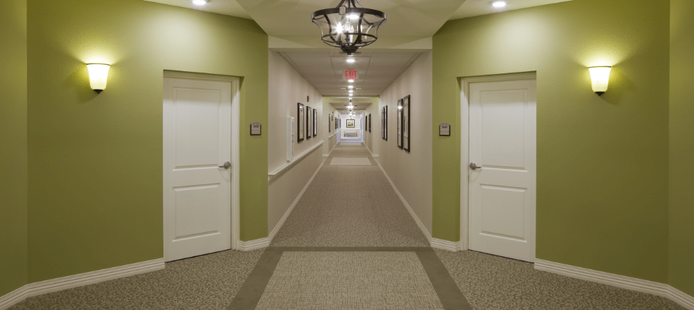 Brightly lit corridor with doors and framed pictures