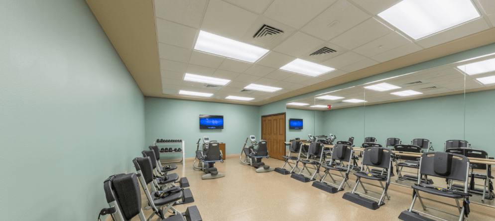 A fitness room with exercise equipment and mirrors