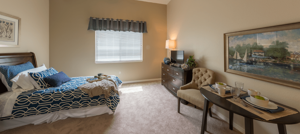 A well-decorated resident room with a bed and table
