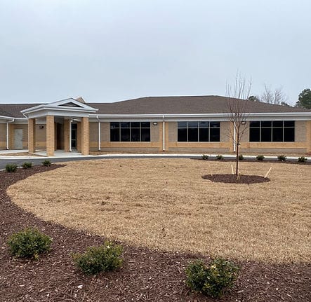 Exterior view of the facility building with landscaped area.