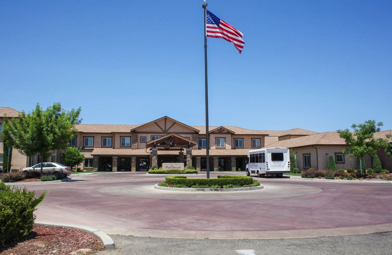 Exterior view of Paintbrush Assisted Living with flag and bus